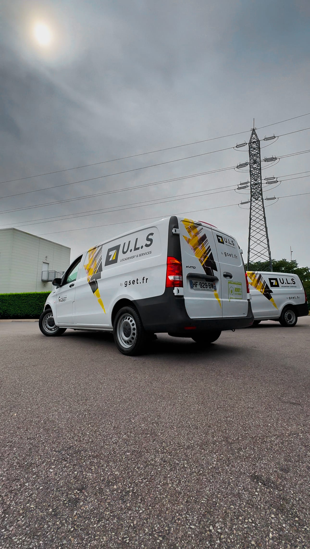 Deux véhicules utilitaires U.L.S stationnés sur un parking, prêts pour une tournée de livraison.