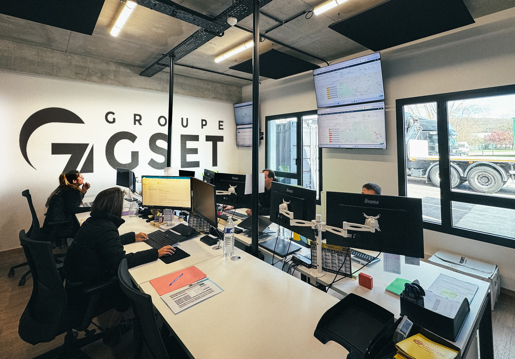Poste de travail dans un open space du Groupe GSET avec plusieurs écrans d’ordinateurs affichant des outils de suivi logistique.