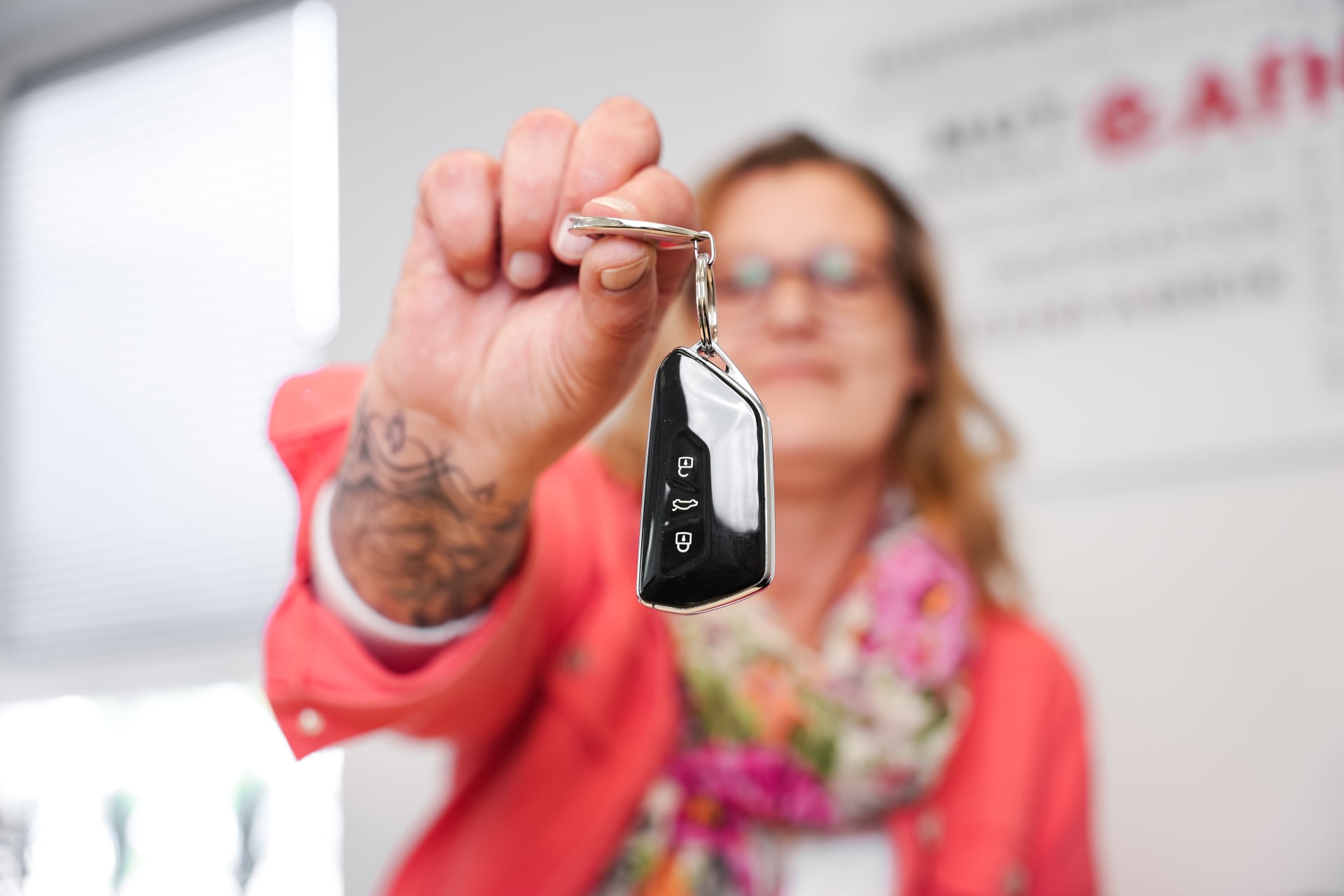 Backoffice-medewerkster houdt de sleutels van de dienstauto voor de camera.