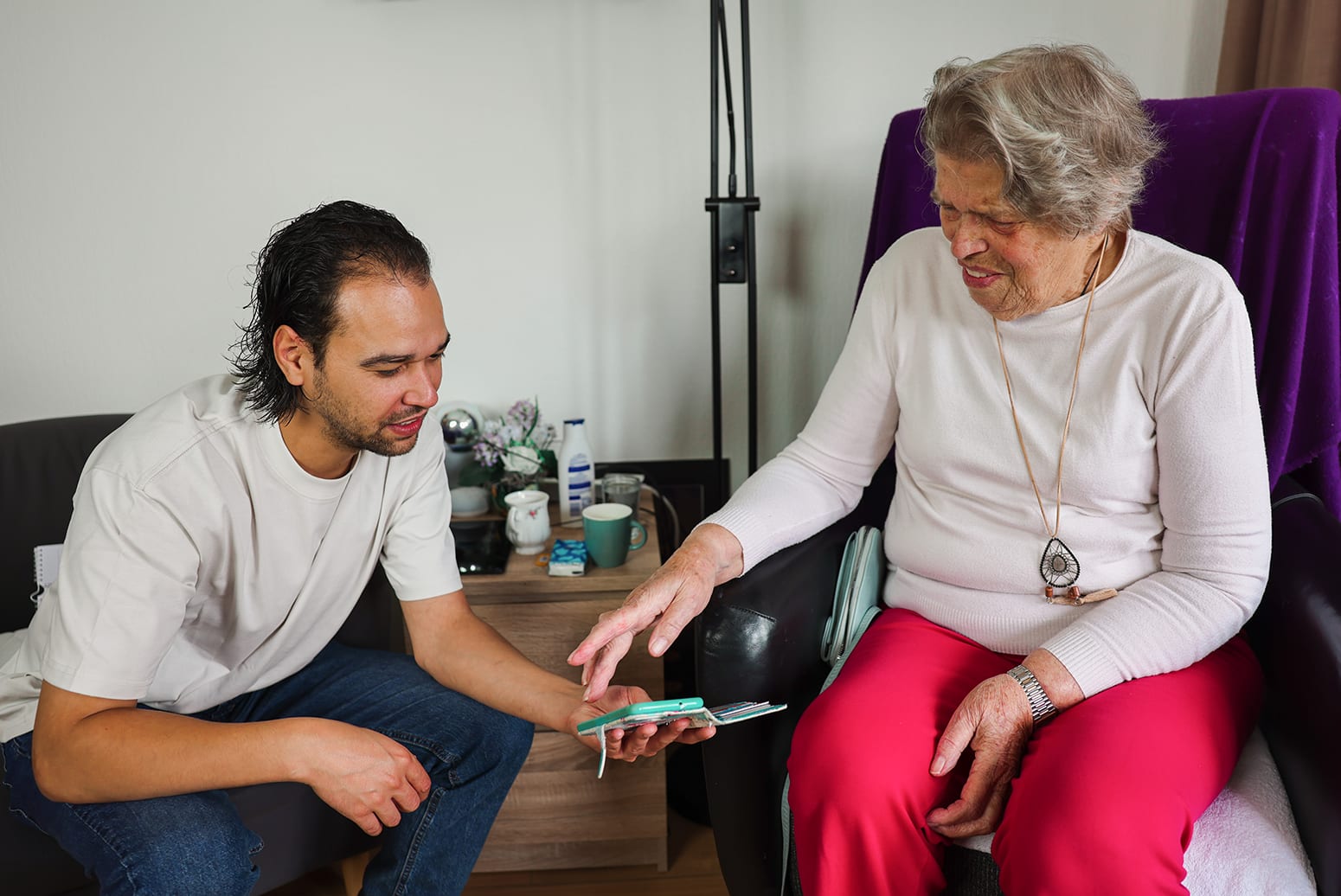 Verpleegkundige met bewoner en telefoon Vertrouwd Thuis