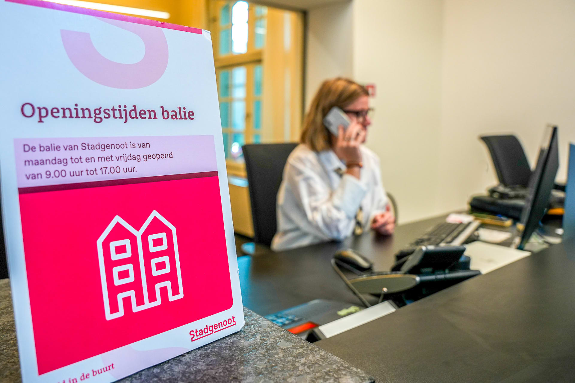 Medewerker aan de telefoon bij de balie