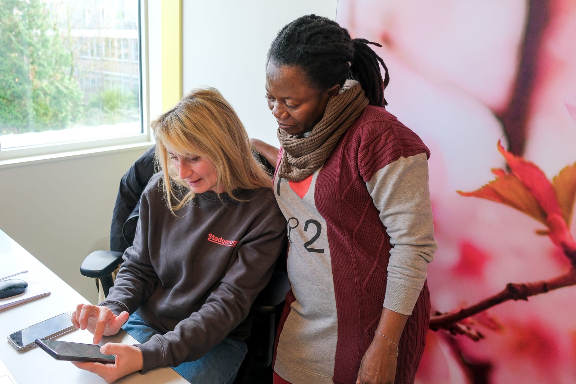 Bewonersbegeleider Flennie legt iets uit aan een bewoner