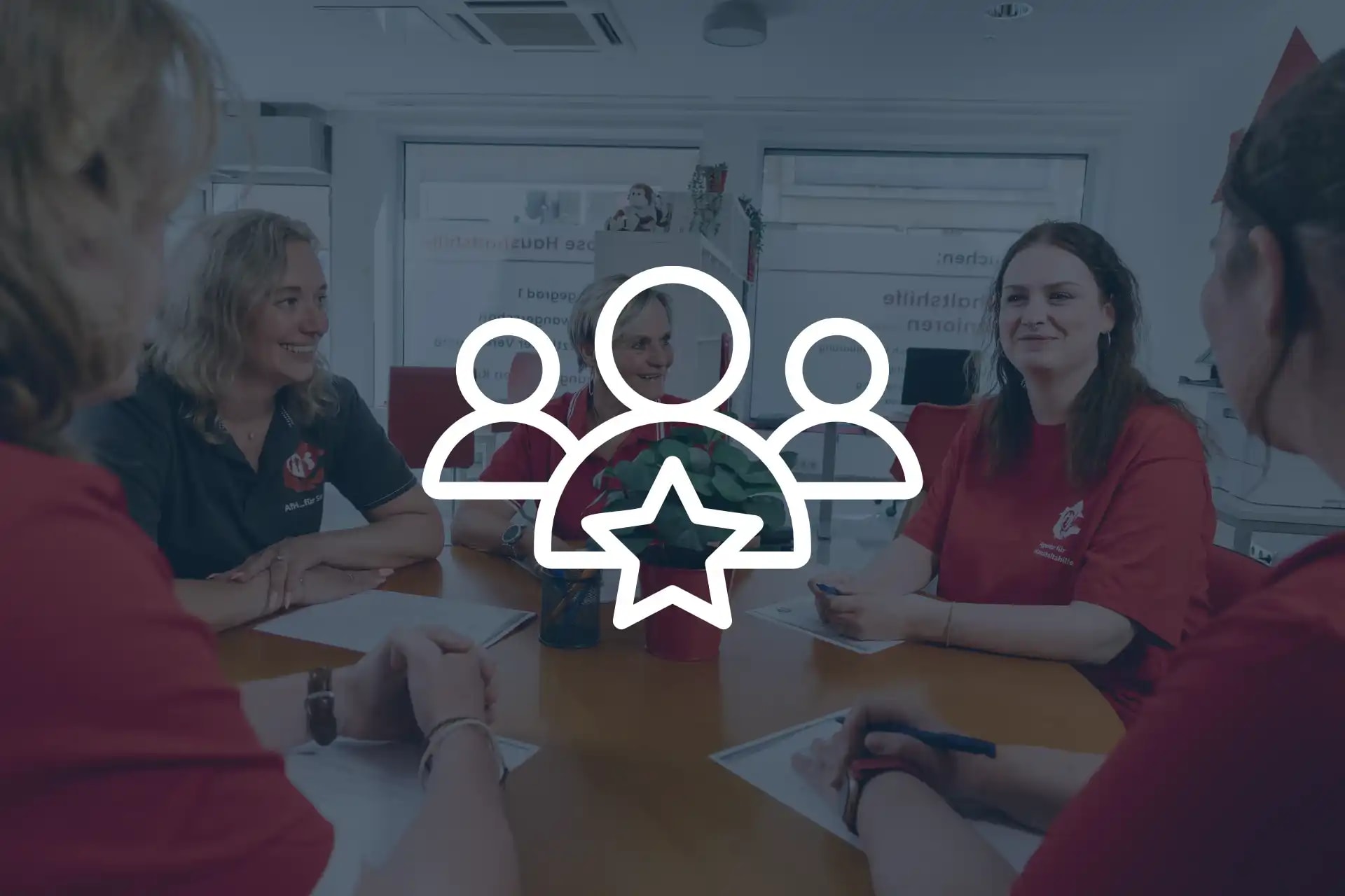 Standort Teamleitung - Teamleitung und Haushaltshelfer sitzen gemeinsam fröhlich beim Teamtreffen am Tisch