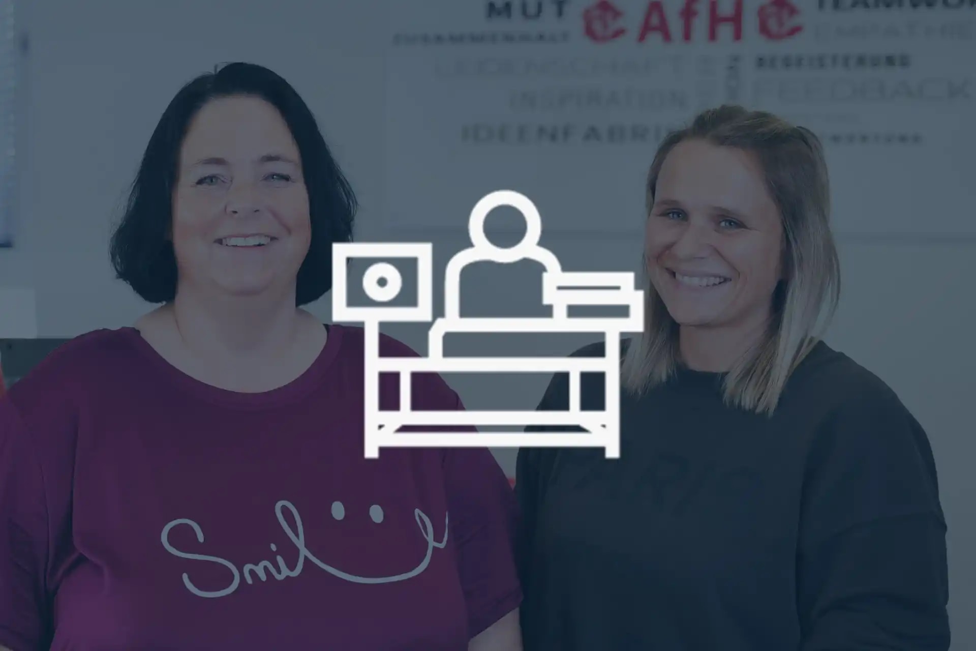 Zwei Mitarbeiterinnen aus der Abteilung Backoffice lachen in die Kamera