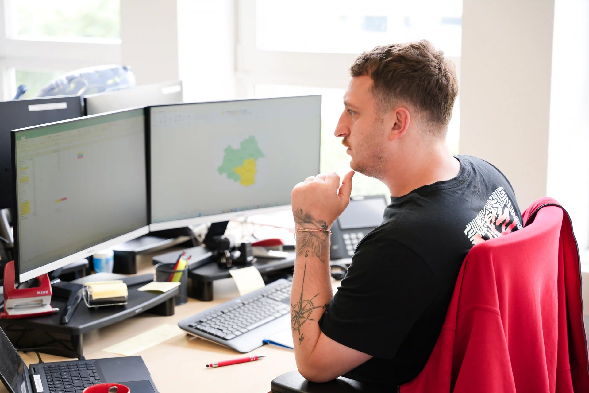 Een medewerker van de afdeling Inside Team Coordination van het Agency For Domestic Help zit aan zijn bureau en kijkt naar twee beeldschermen.