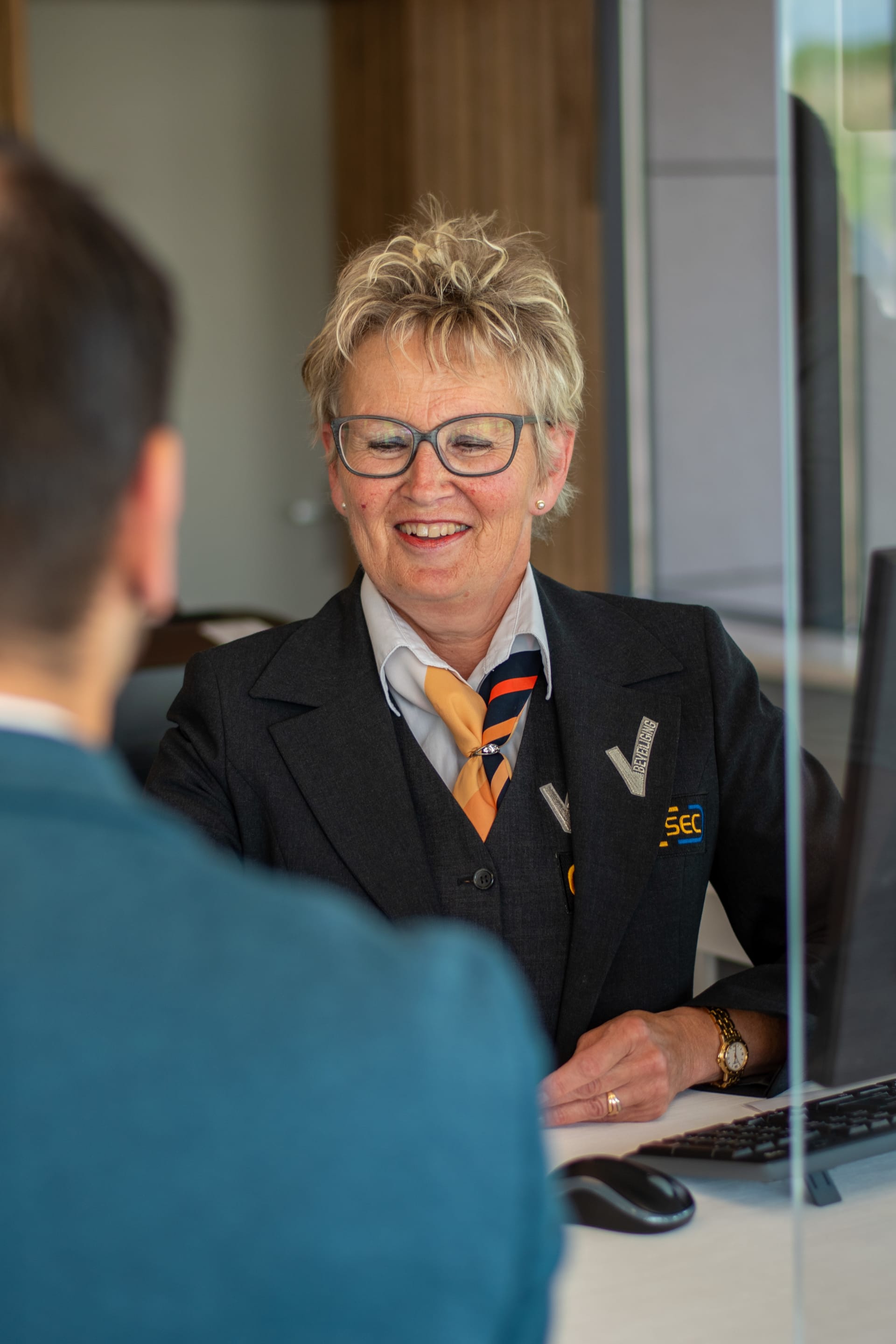 Vrouwelijke luchthavenmedewerker van I-SEC met een sjaaltje glimlachend binnen in een kantoor