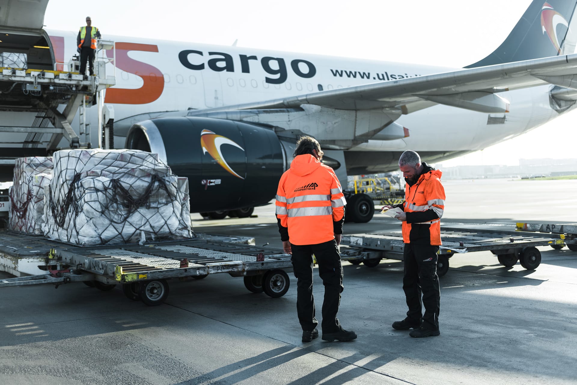twee Aviapartner medewerkers staan bij een Cargo vliegtuig dat geladen wordt