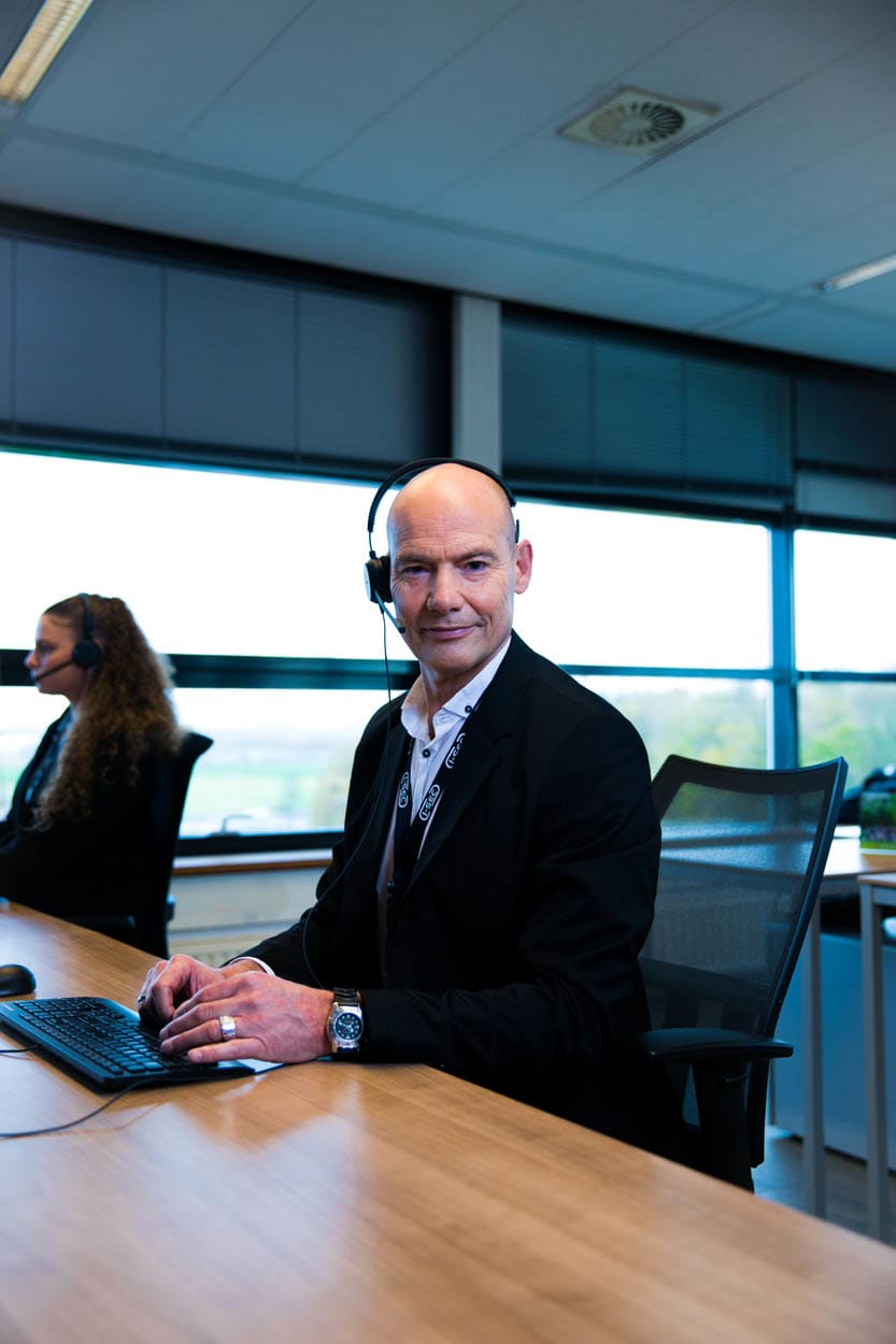 Een man in een headset werkt aan een computer in een kantooromgeving, wat wijst op klantenservice of een callcenter-rol.
