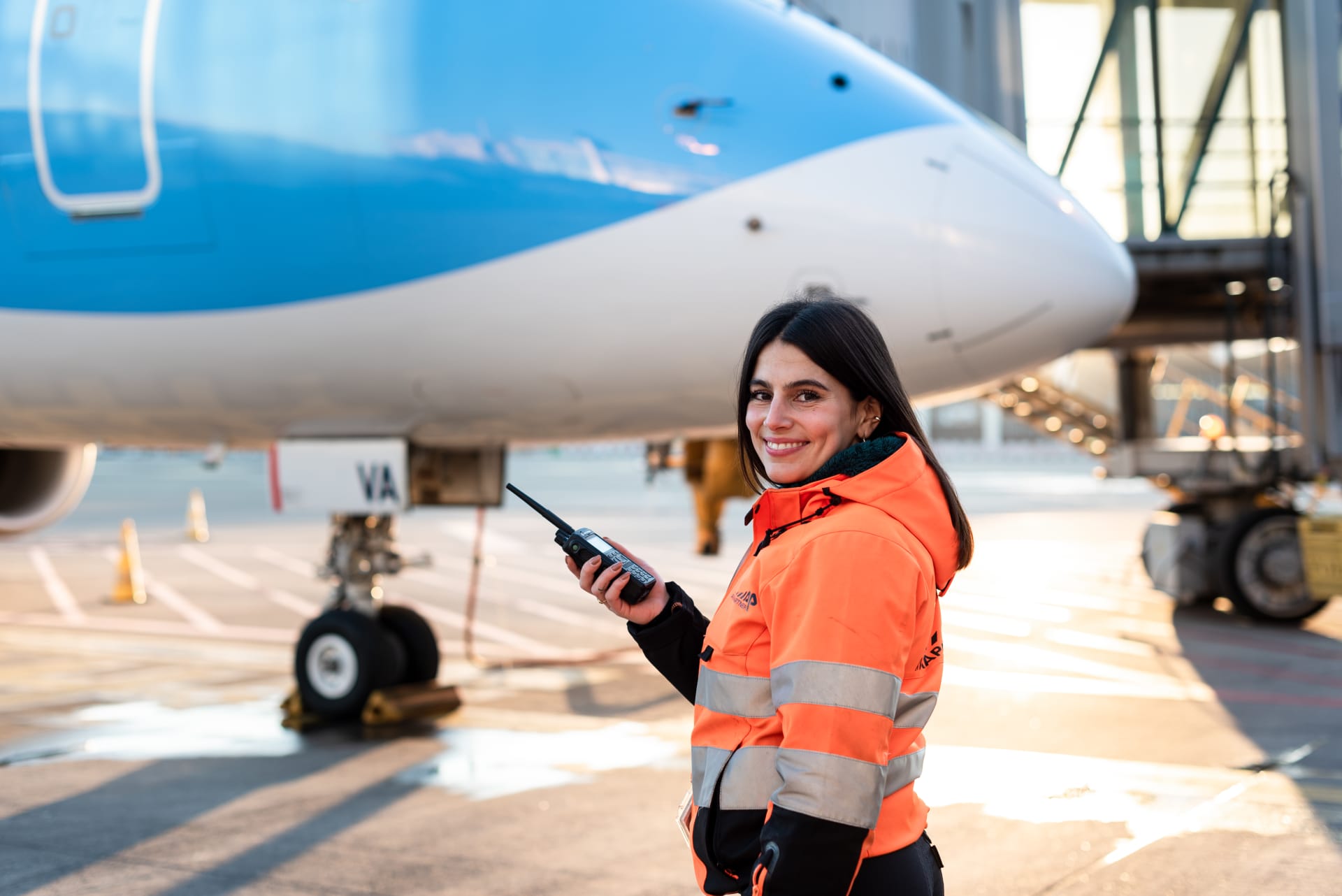 A Turnaround Coordinator at Aviapartner stand in front of a TUI plane on tarmac at Brussels Airport holding a trunk to communicate