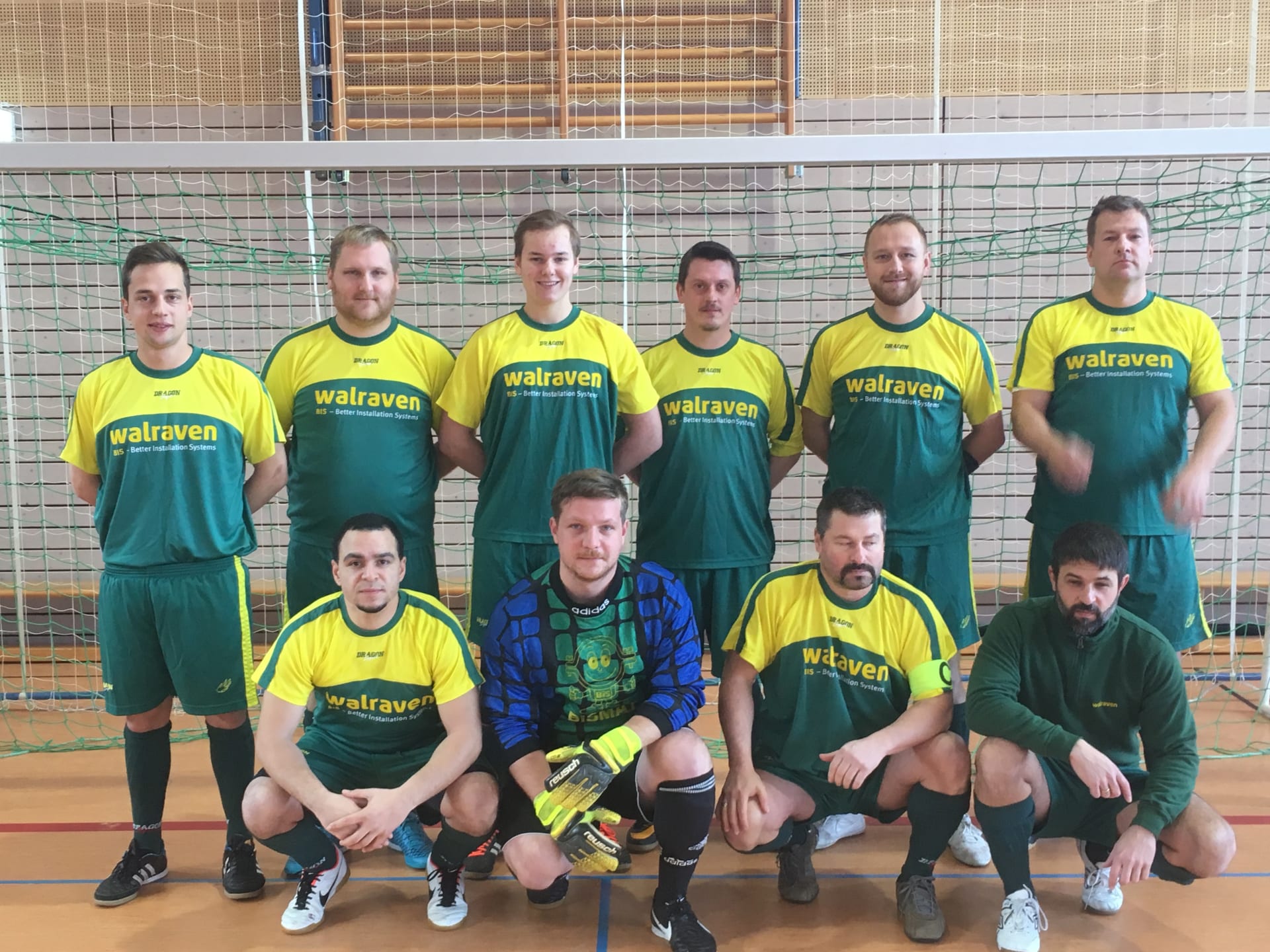 Mannschaftsfoto des Hallenfußball-Teams der Walraven GmbH mit neun Feldspielern und einem Torwart in gelb-grünen Trikots, entstanden bei einem Spaßturnier.