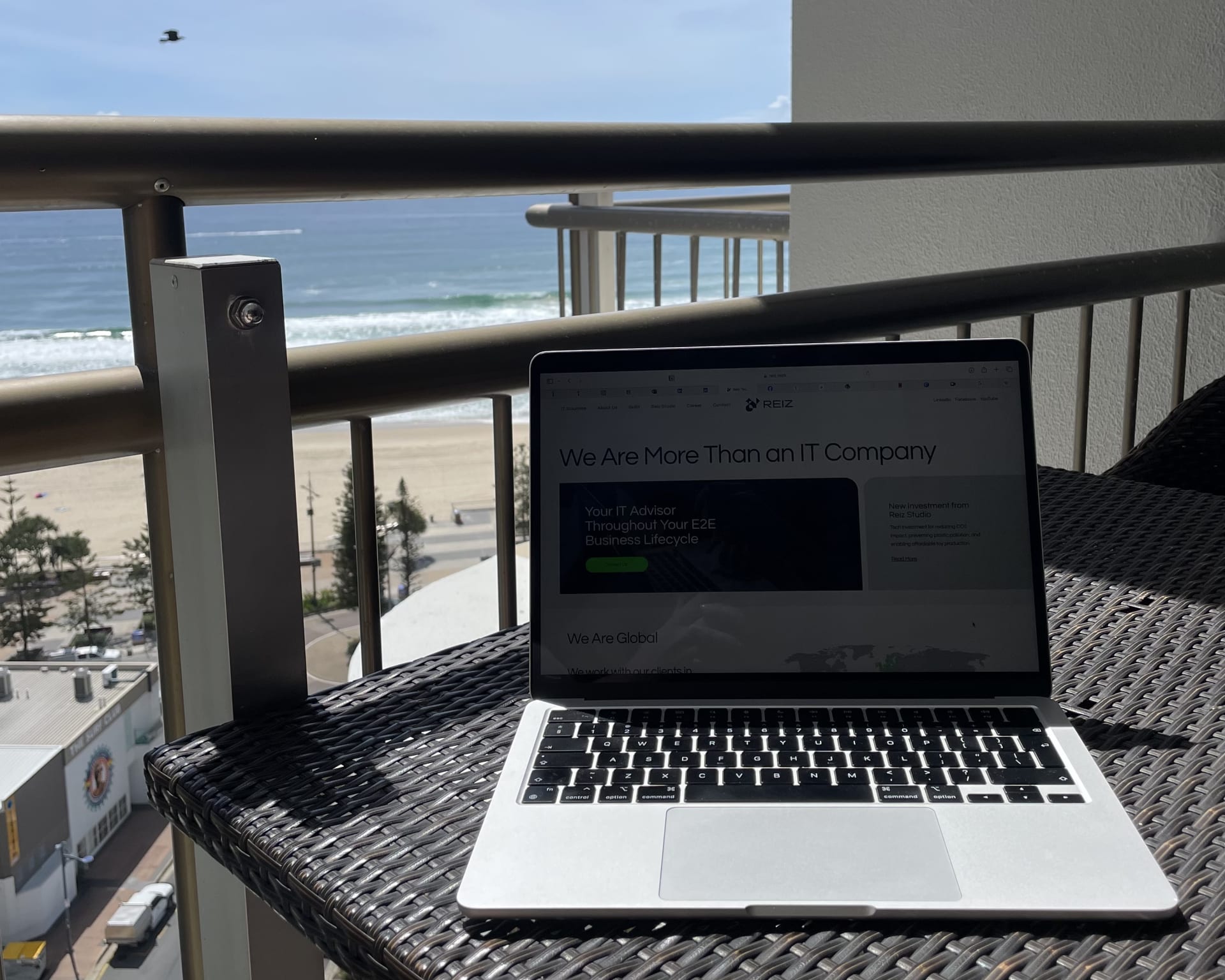 laptop, with Reiz Tech website, beach in the background