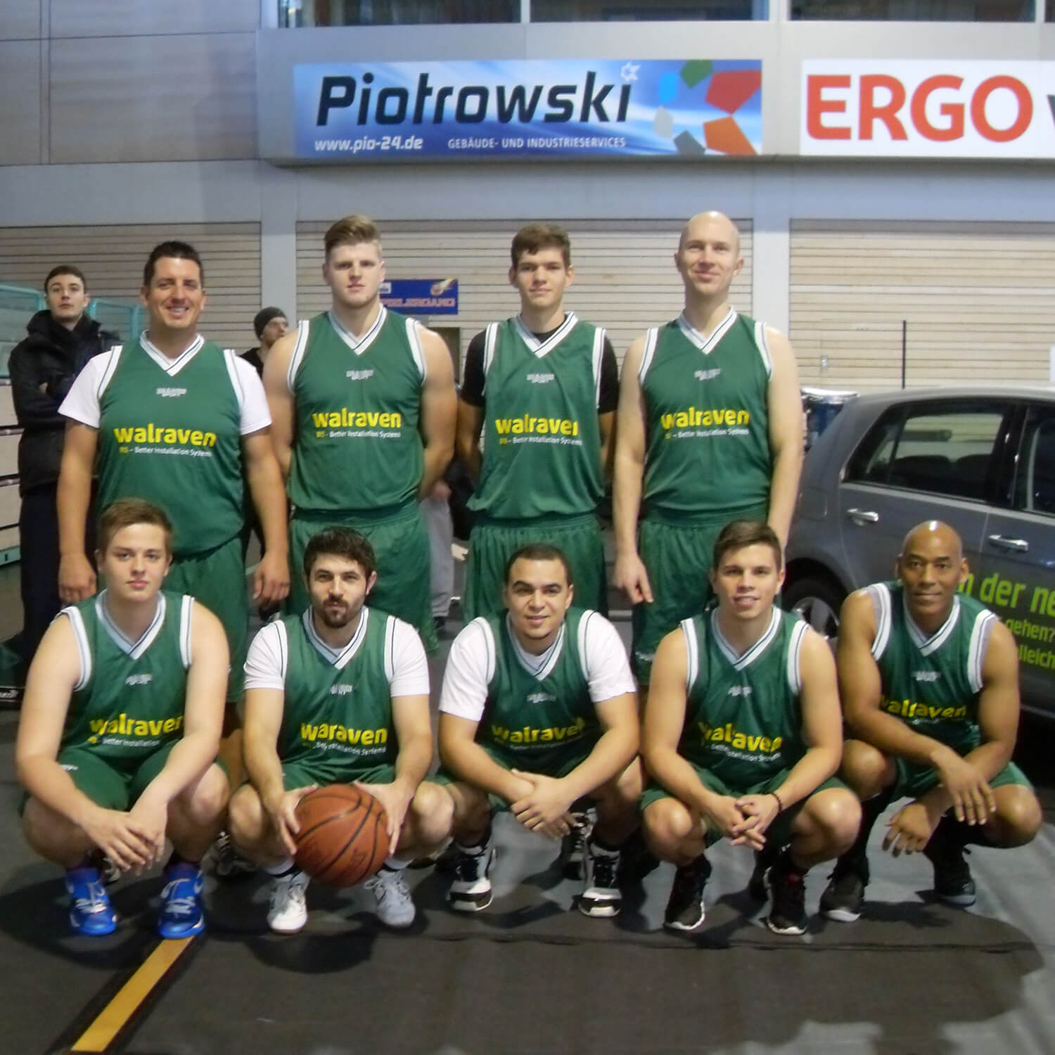 Teamfoto des Basketball Firmenteams der Walraven GmbH, entstanden bei einem Spaßturnier. Abgebildet sind neun Mitarbeiter in grünen Jerseys in zwei Reihen, ein Spieler hält einen Basketball.