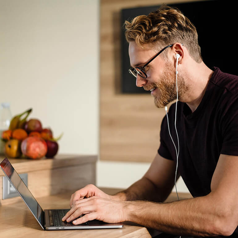 Ein Mann sitzt vor seinem Laptop und befindet sich dabei in einer Online-Besprechung. Das Bild visualisiert den Walraven-Benefit "Mobile Arbeitsmodelle".