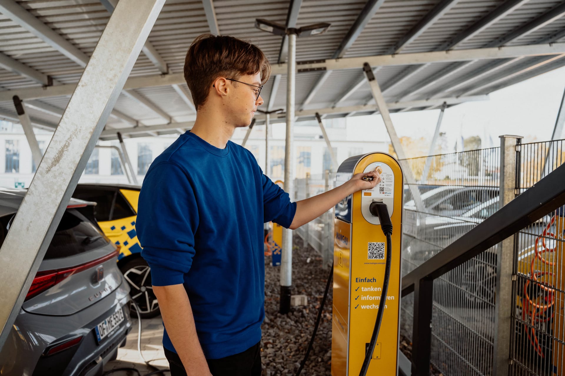 Ein Mann schließt sein Auto an eine Ladestation an