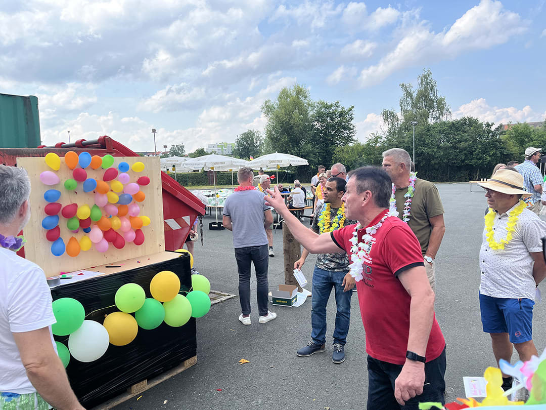 Walraven Sommerfest 2024 - Mitarbeiter wirft mit Dartpfeilen auf Ballons bei der Walraven-Olympiade