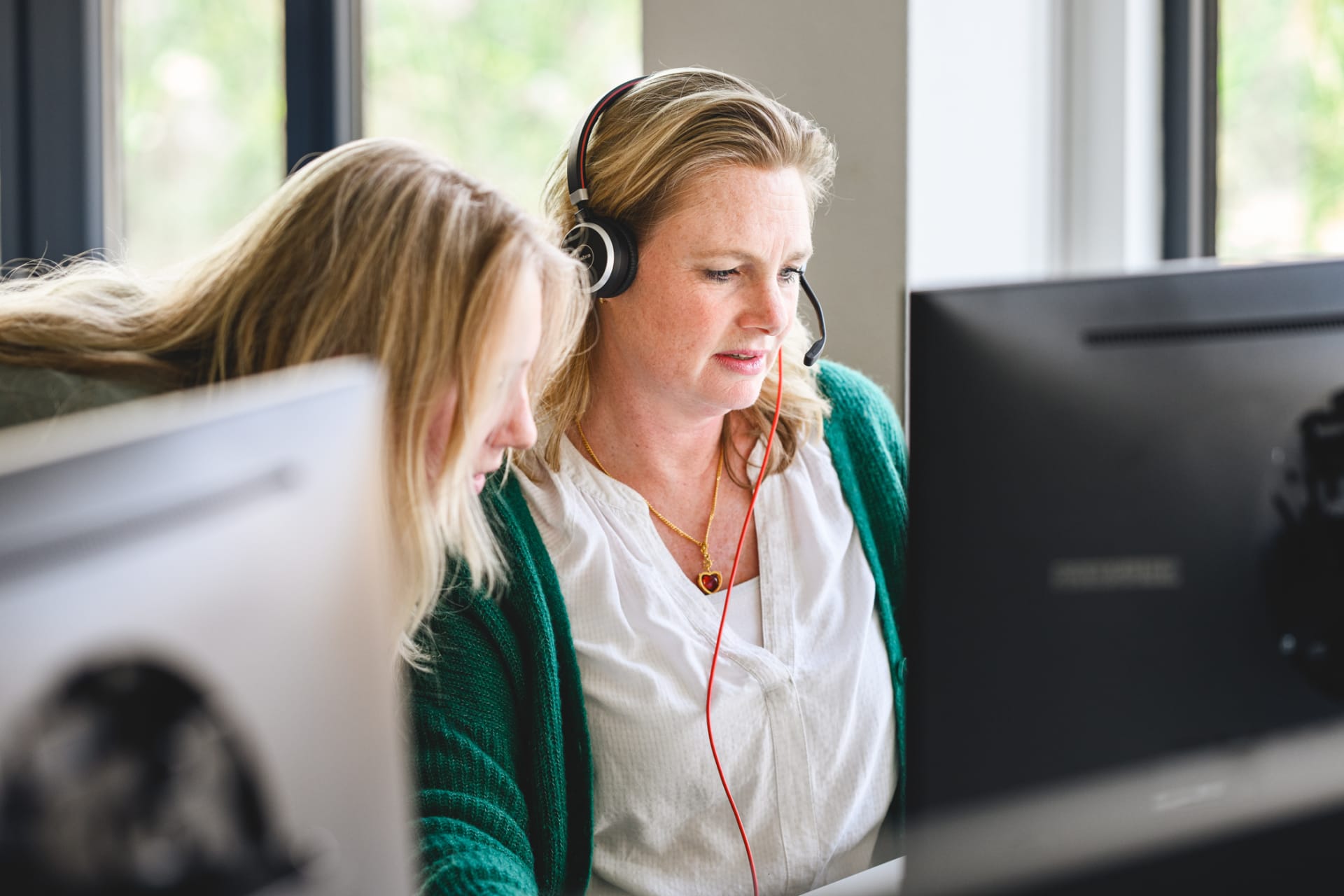 Vrouw met headset op, geholpen door collega