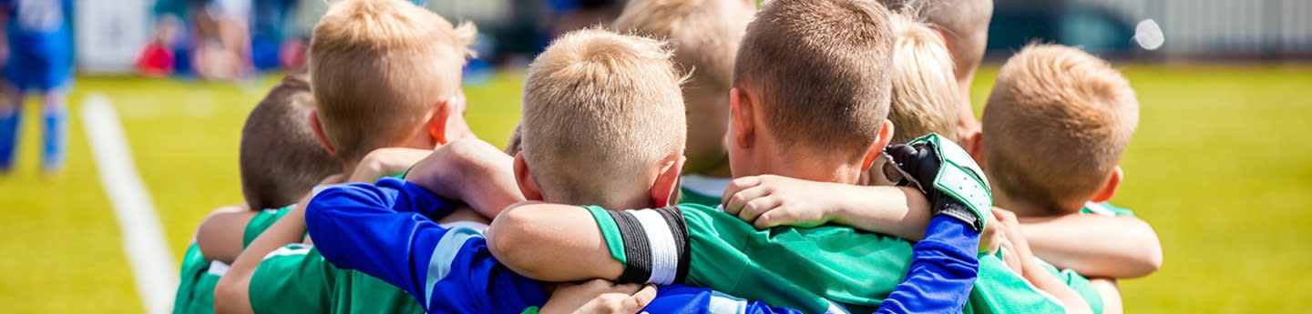 Een paar blonde jongetjes omhelzen elkaar op het voetbalveld