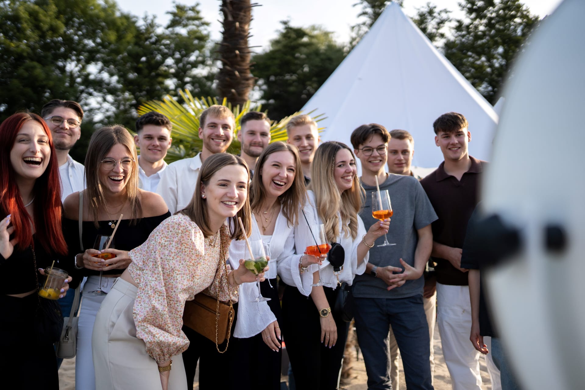 Eine Gruppe Nachwuchskräfte mit Getränken in der Hand vor einer Fotobox.