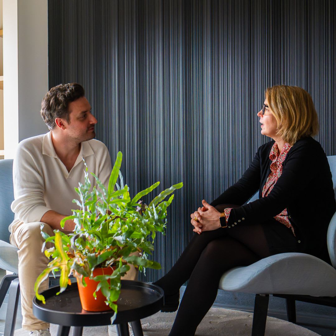 two colleagues talking and sitting on a chair