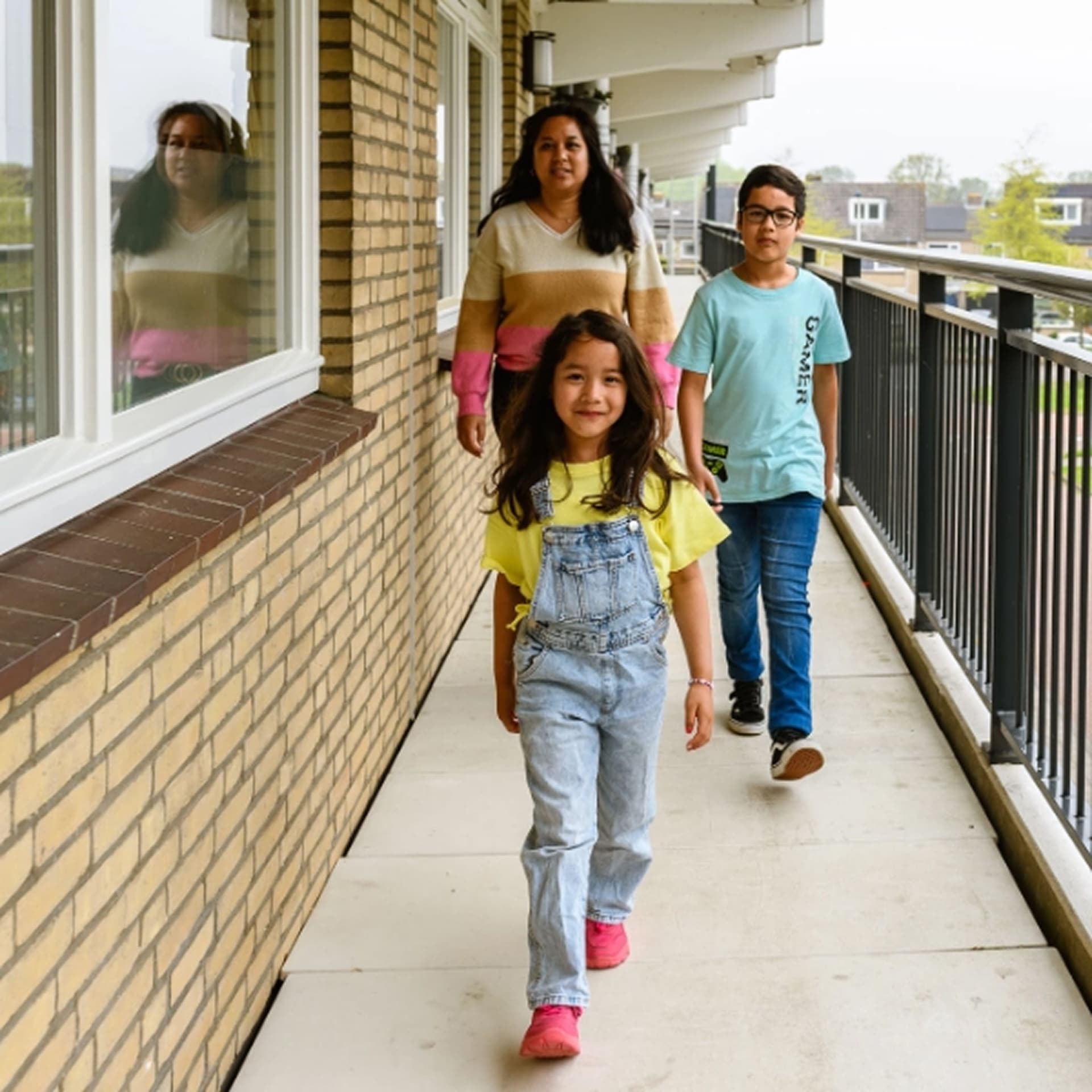 Moeder met 2 kinderen lopen in een flatgebouw