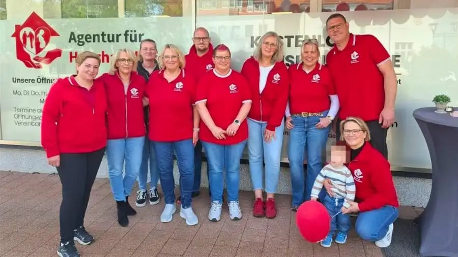 Group photo of the Agency for Household Help team gathered at the office opening in Petershagen, standing together with District Manager Kathrin Smoes and celebrating the new location.