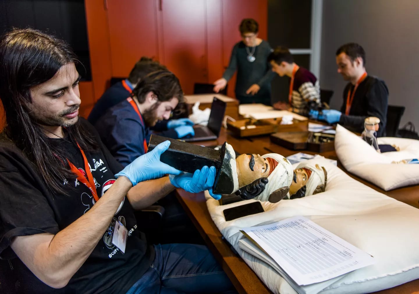 Onderzoekers met handschoenen bestuderen houten beelden uit de collectie