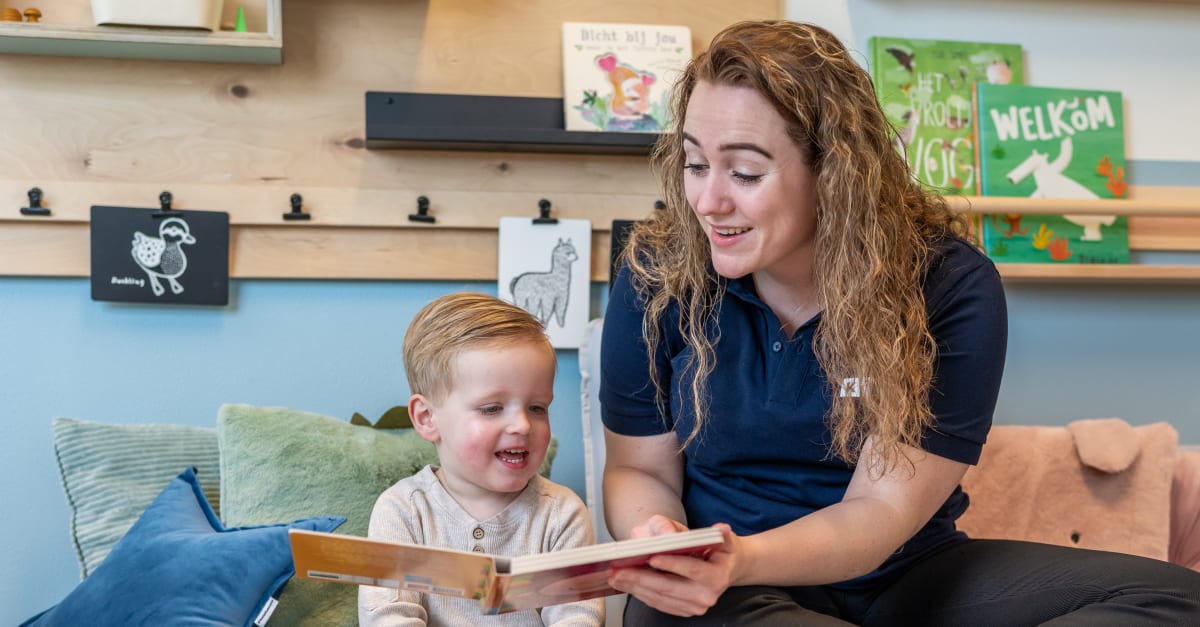 Een pedagogisch professional leest een boekje voor aan een peuter