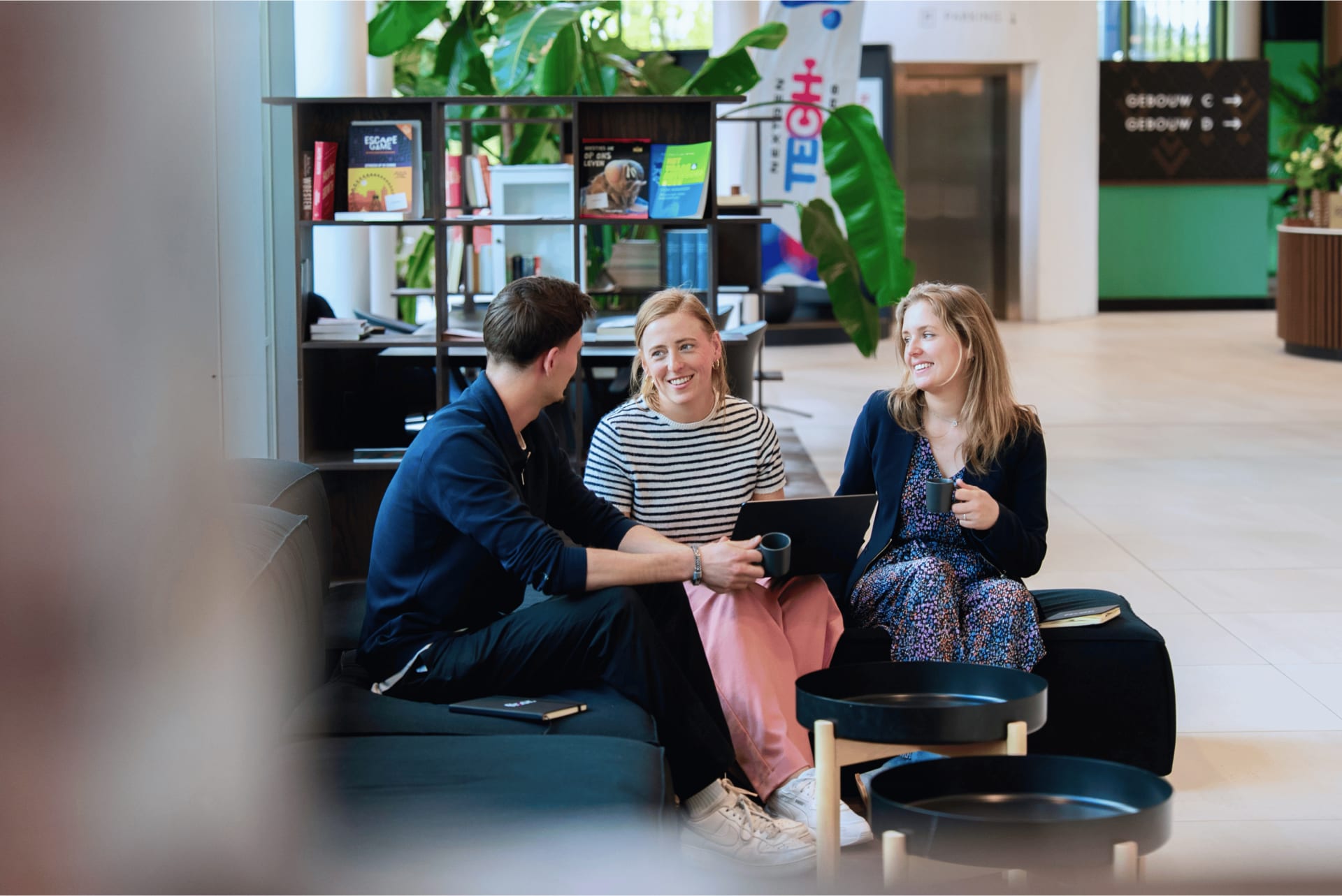 Drie lachende collega's in gesprek op een bank
