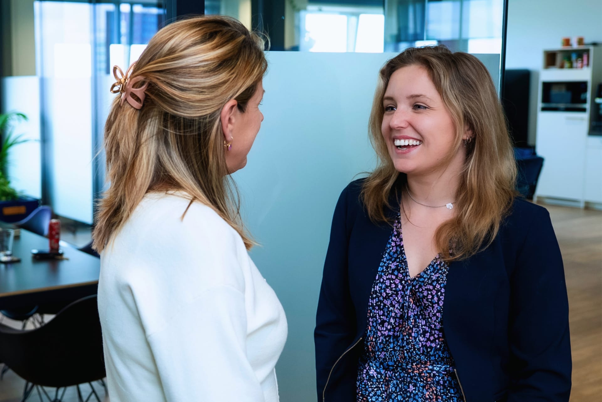 Twee collega's in gesprek buiten een vergaderruimte