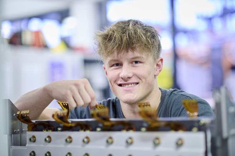 Ein junger Mann hält mit einer Hand elektronisches Bauteil.