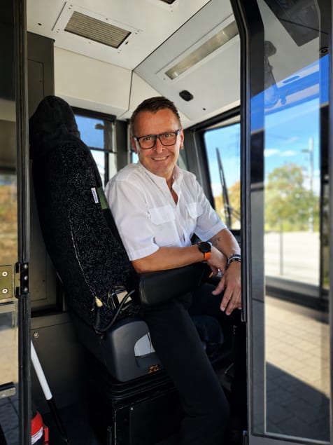 Lächelnder Mitarbeiter der Graz Linien sitzt auf dem Fahrerplatz einer Straßenbahn.